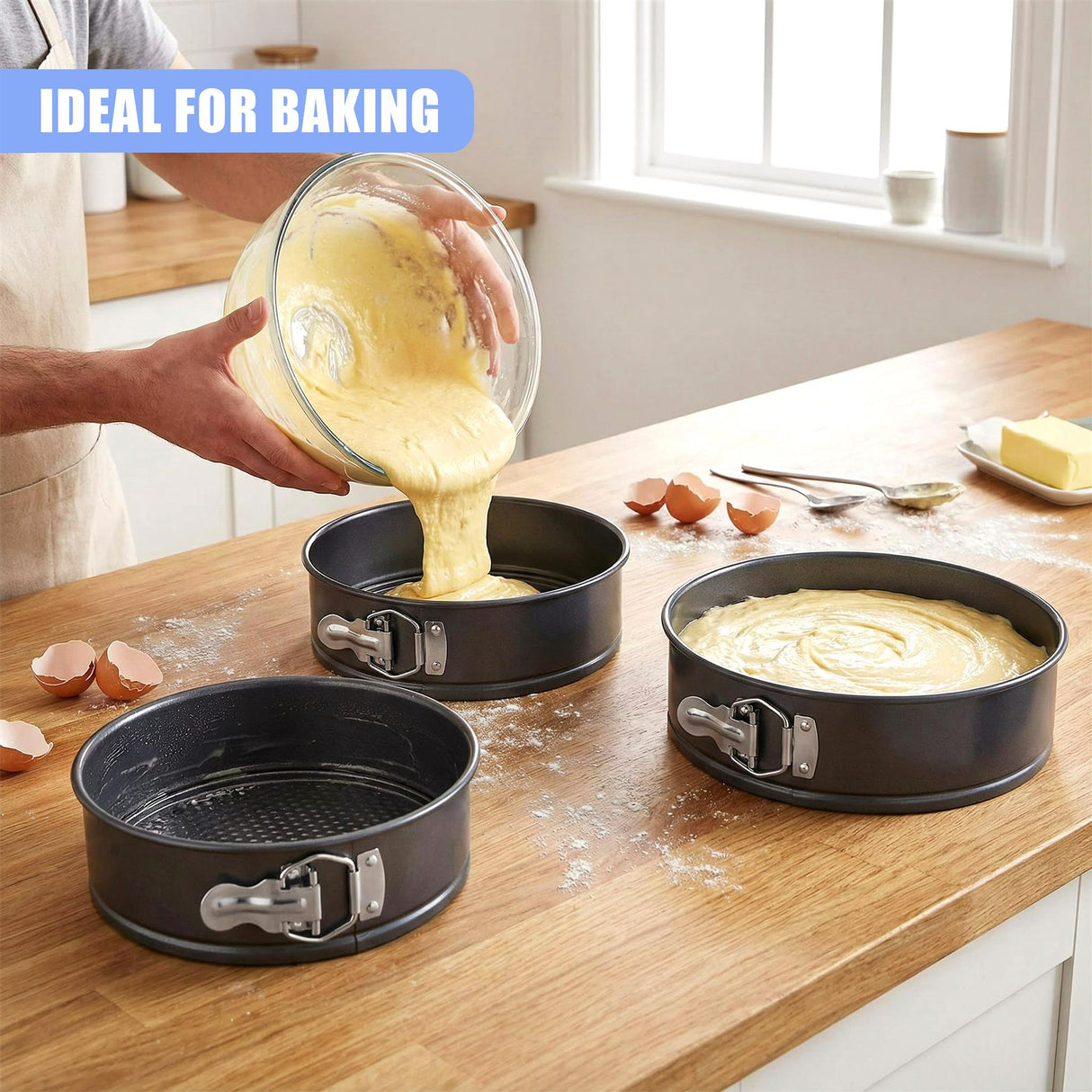 Kitchen countertop displays three springform cake pans and batter being poured into one.