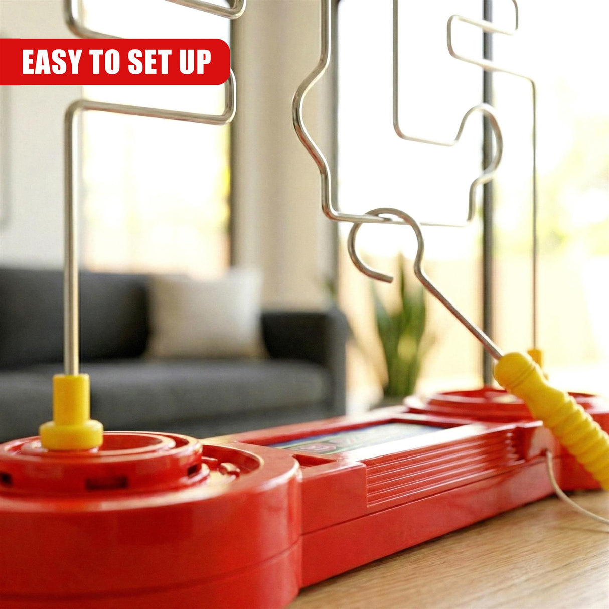 Red plastic console holding a flexible metal grid and a yellow buzzer handle.