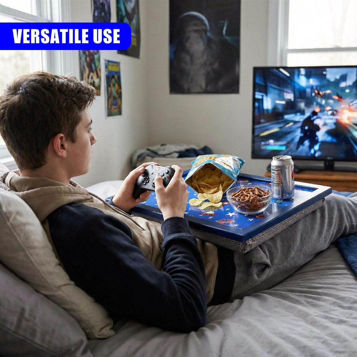 Lap tray set up on a bed holding snacks, drink, and controller while a person plays video games.