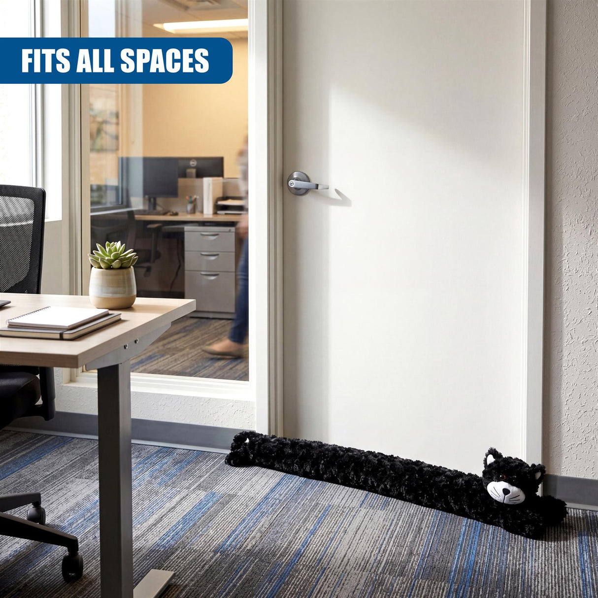 Black novelty cat draught excluder rests on light wood floor near white door.