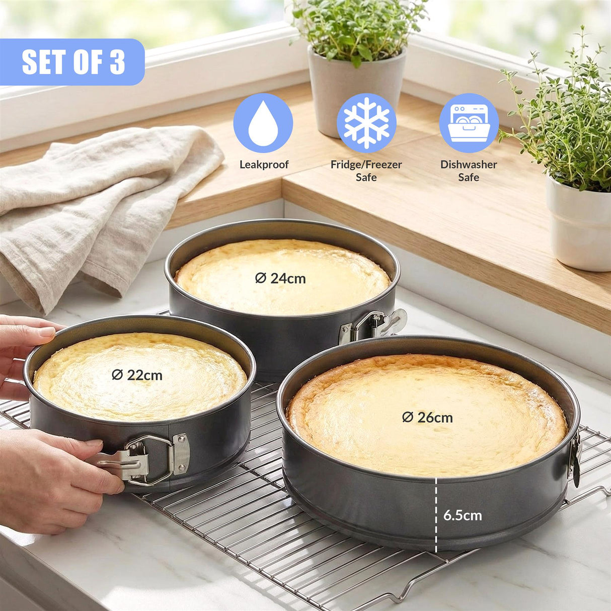 Three black circular metal baking tins of varying diameters are displayed on a silver wire cooling rack.