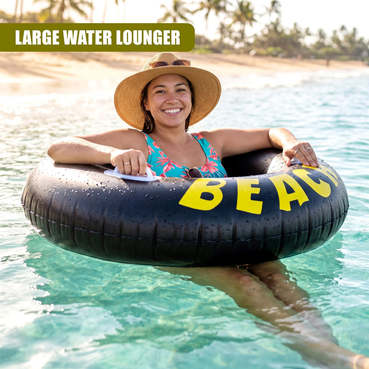 Smiling woman sitting in a large black inflatable tube floating in clear ocean water near a beach.
