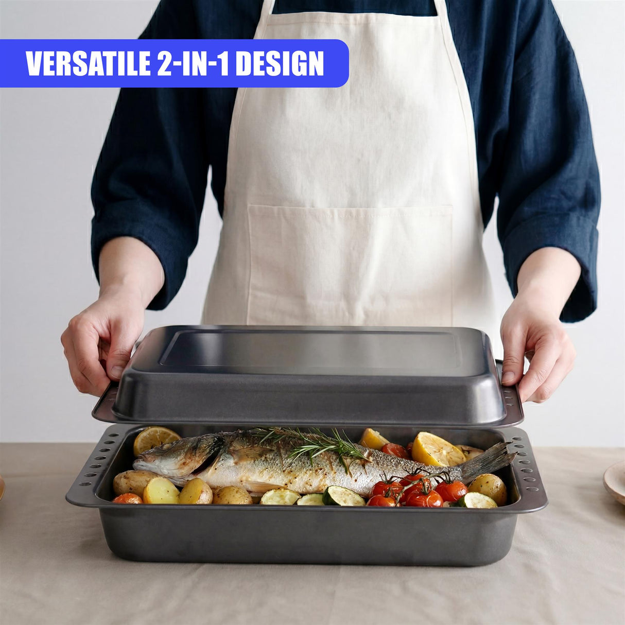 An open metal roasting pan holds roasted fish, potatoes, and various vegetables.