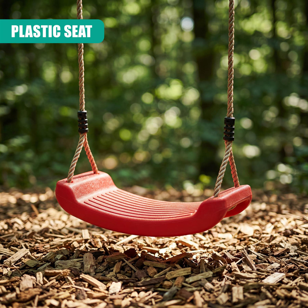 Curved red plastic swing seat hangs by braided ropes against a natural, wooded backdrop of mulch.