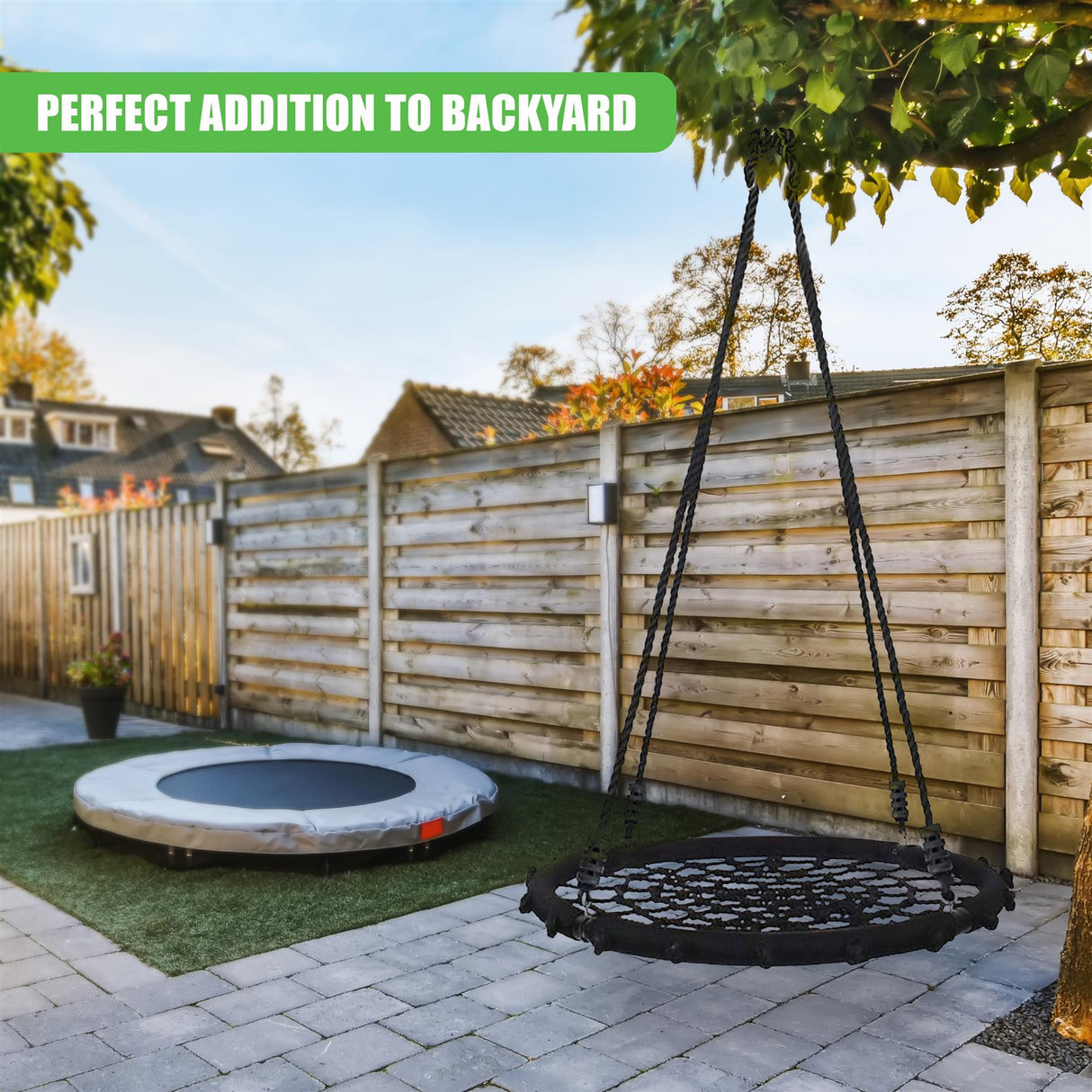 A black hanging nest swing and a ground-based circular swing are set in a fenced backyard patio.