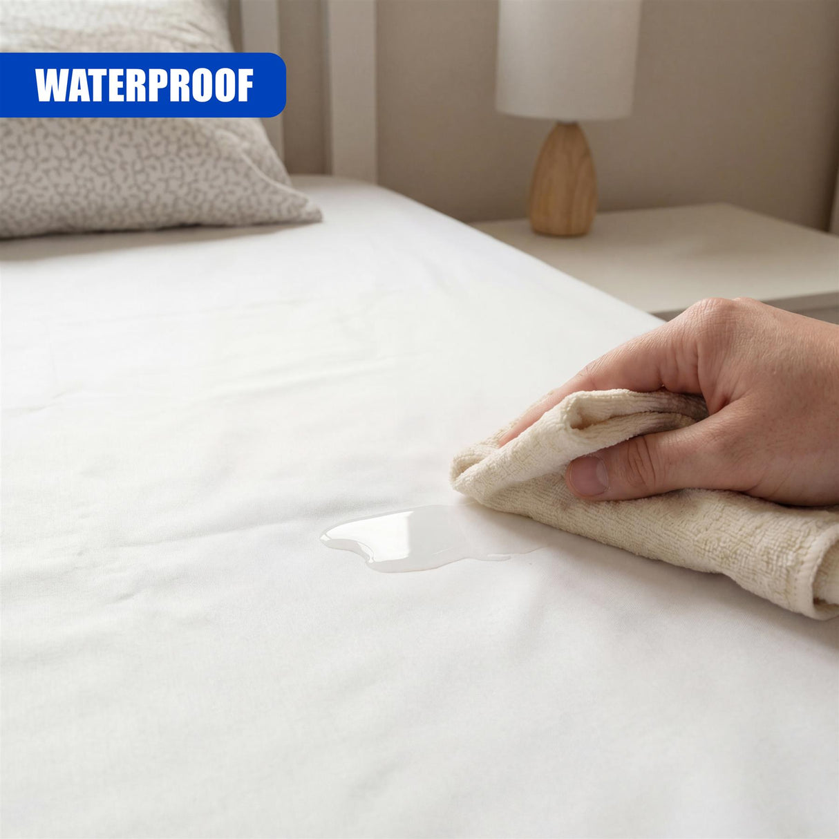 A hand uses a folded cloth to pick up a visible droplet of liquid on the white bed sheet.