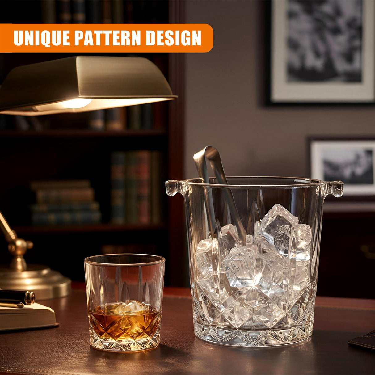 A whiskey glass holding amber liquid rests near a clear, patterned ice bucket filled with ice cubes.