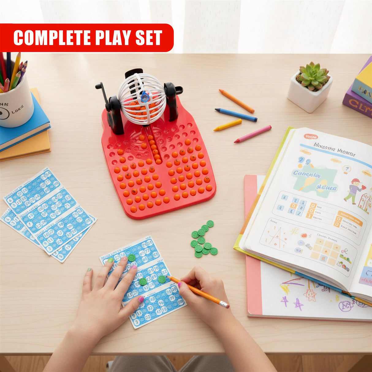 Hands play with a red bingo lotto board, blue cards, and writing tools on a table.