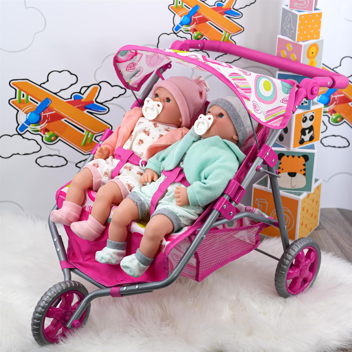 Pink twin doll stroller with two seated dolls, featuring pink and mint green outfits.