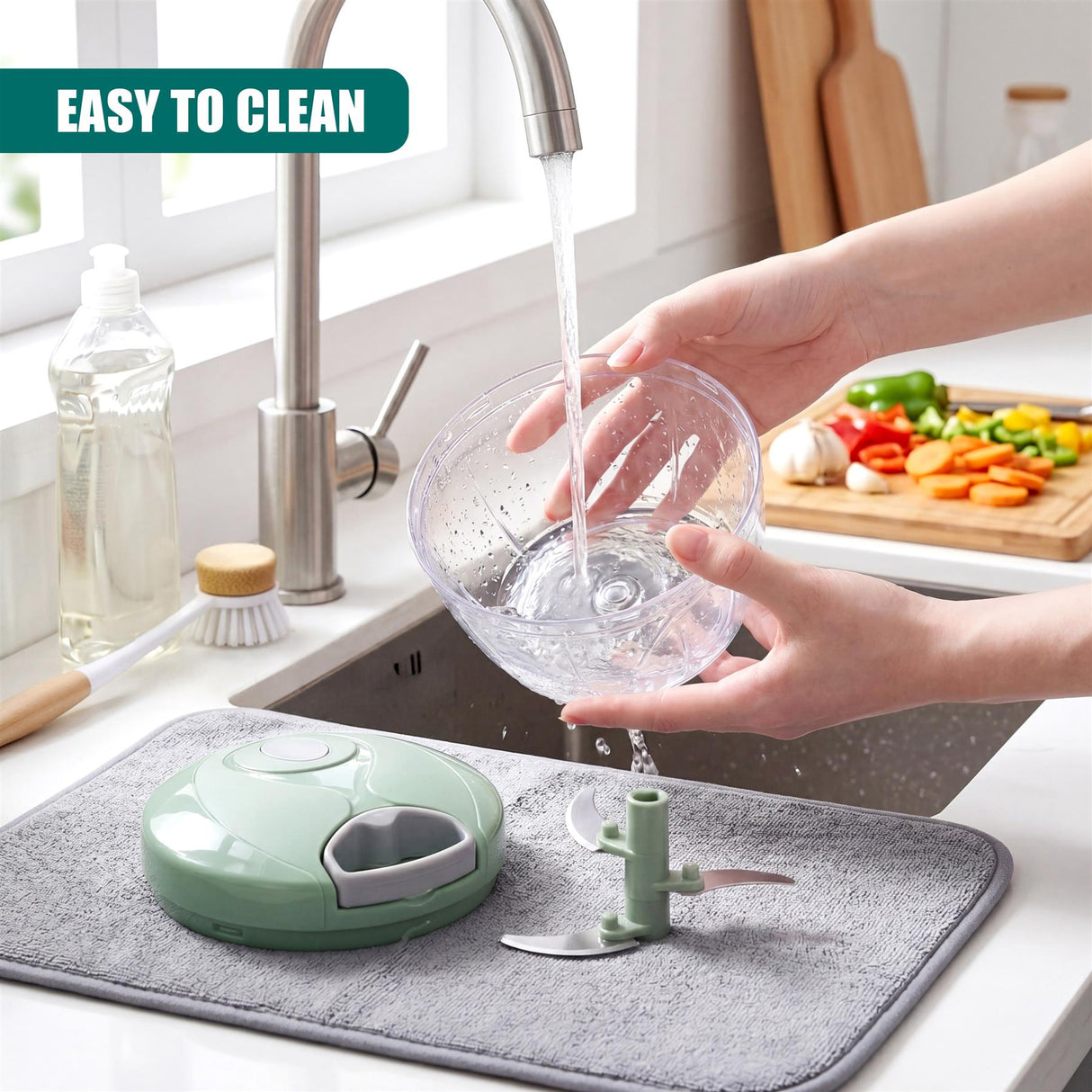 Hands wash a glass food chopper bowl under running water next to a green chopper unit.