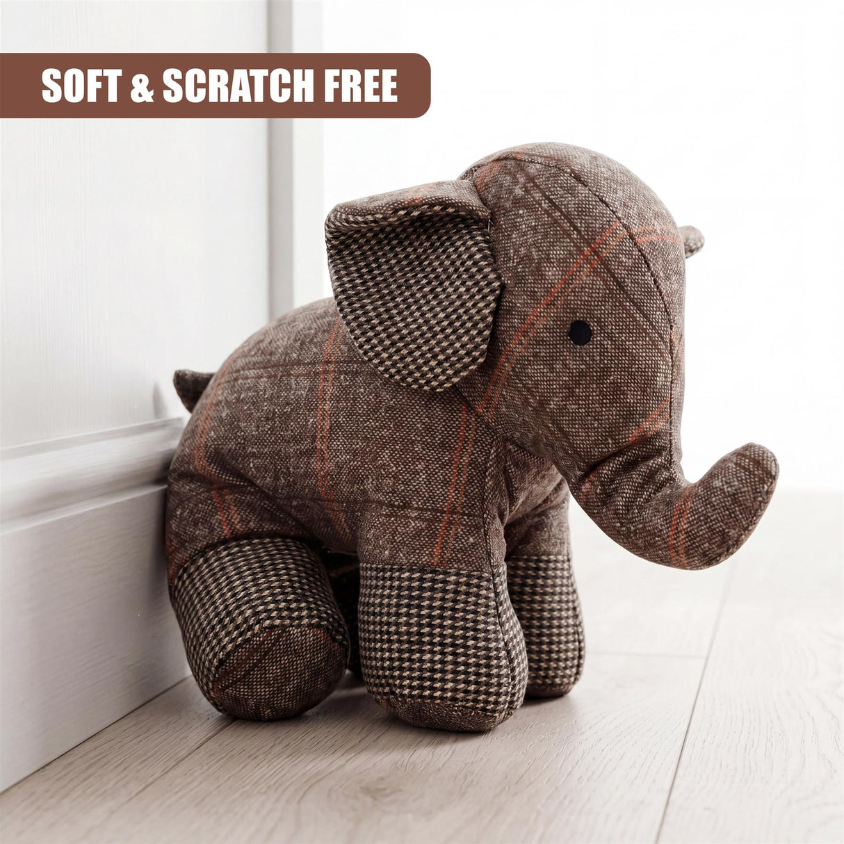 Plaid fabric elephant figure designed as a door stopper near a white baseboard.