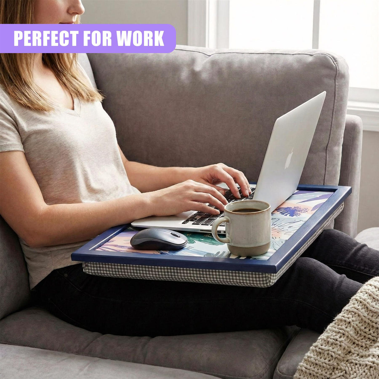 A woman sits on a couch, using a tray with a laptop, mouse, and cup of coffee. The tray is a sturdy, portable workspace with a built-in cup holder and a comfortable, cushioned surface. It is a perfect solution for working or studying from home. - UKBuyZone
