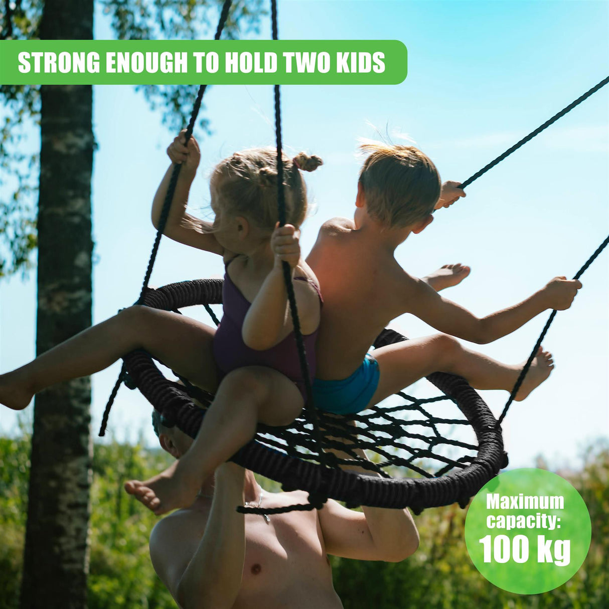 Two children swing on a dark, netted swing suspended outdoors from a pole.
