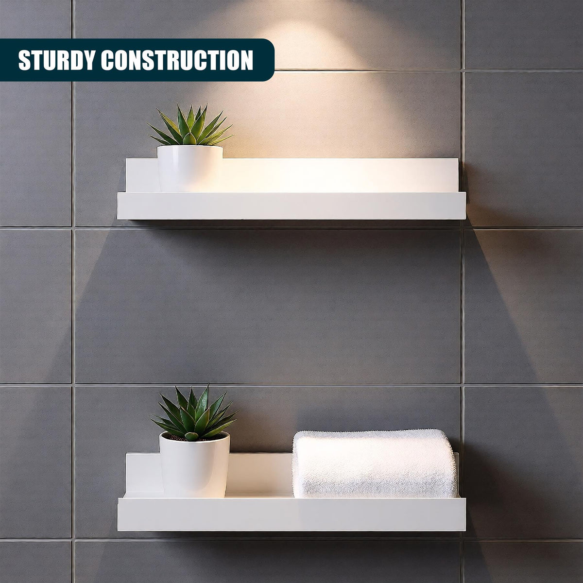 Two white floating shelves mounted on a grey tiled wall, each holding a small potted plant and a folded towel