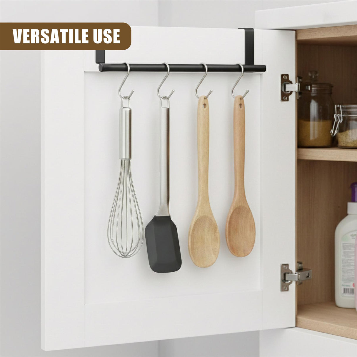 A black rail mounted on a white cabinet holds four hanging kitchen tools: whisk, spatula, and two spoons.