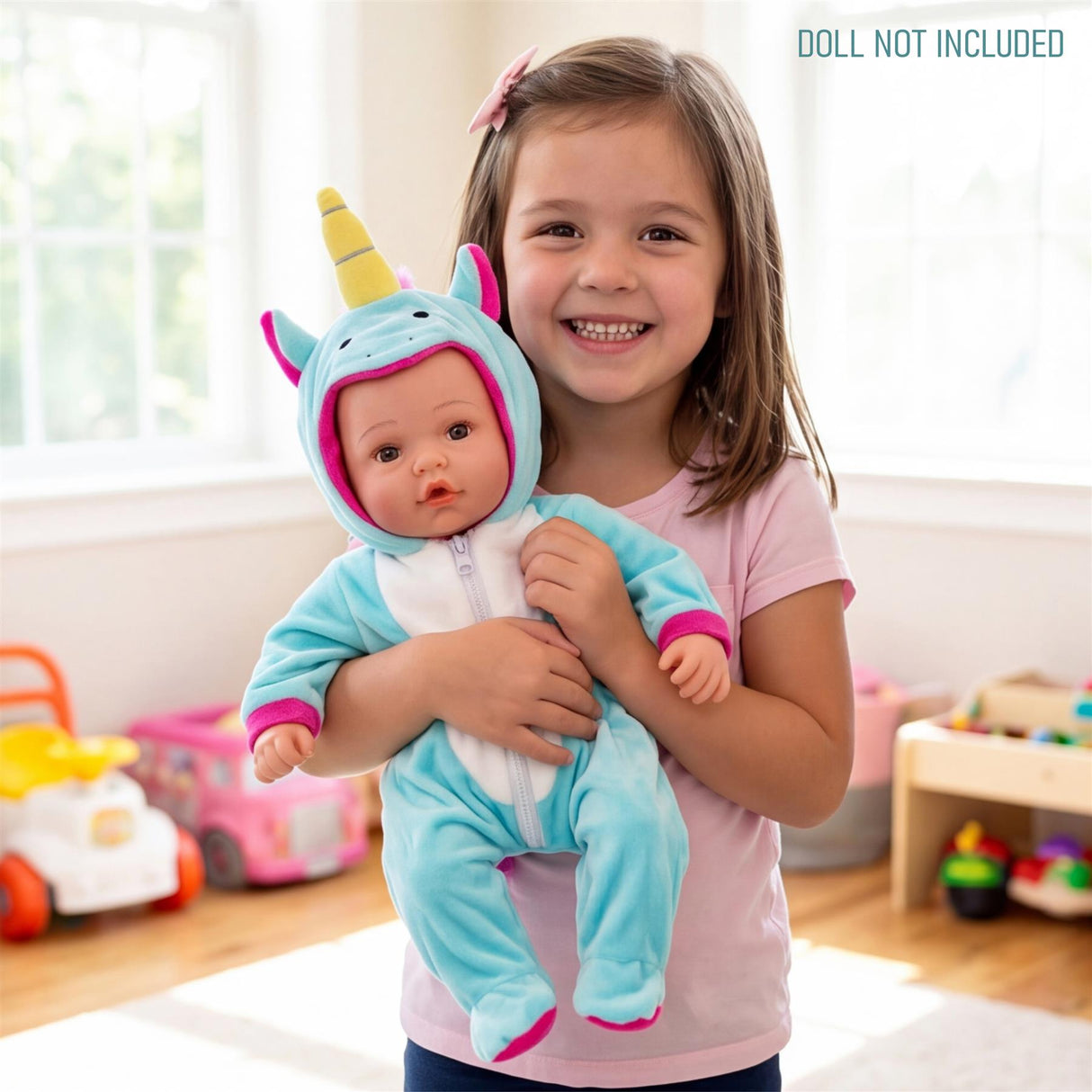 Doll wearing a turquoise unicorn outfit, including a horn and ears, is held by a smiling young girl.