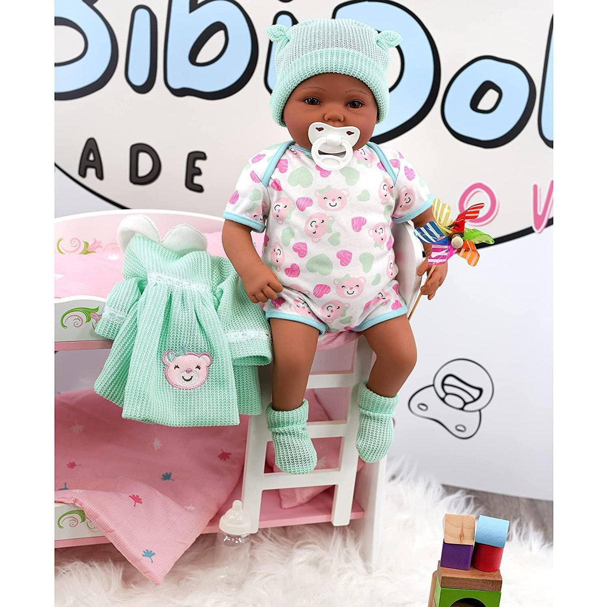 "Babydoll's pink dress and blue blanket, sitting on a pink doll bed with wooden blocks." - UKBuyZone