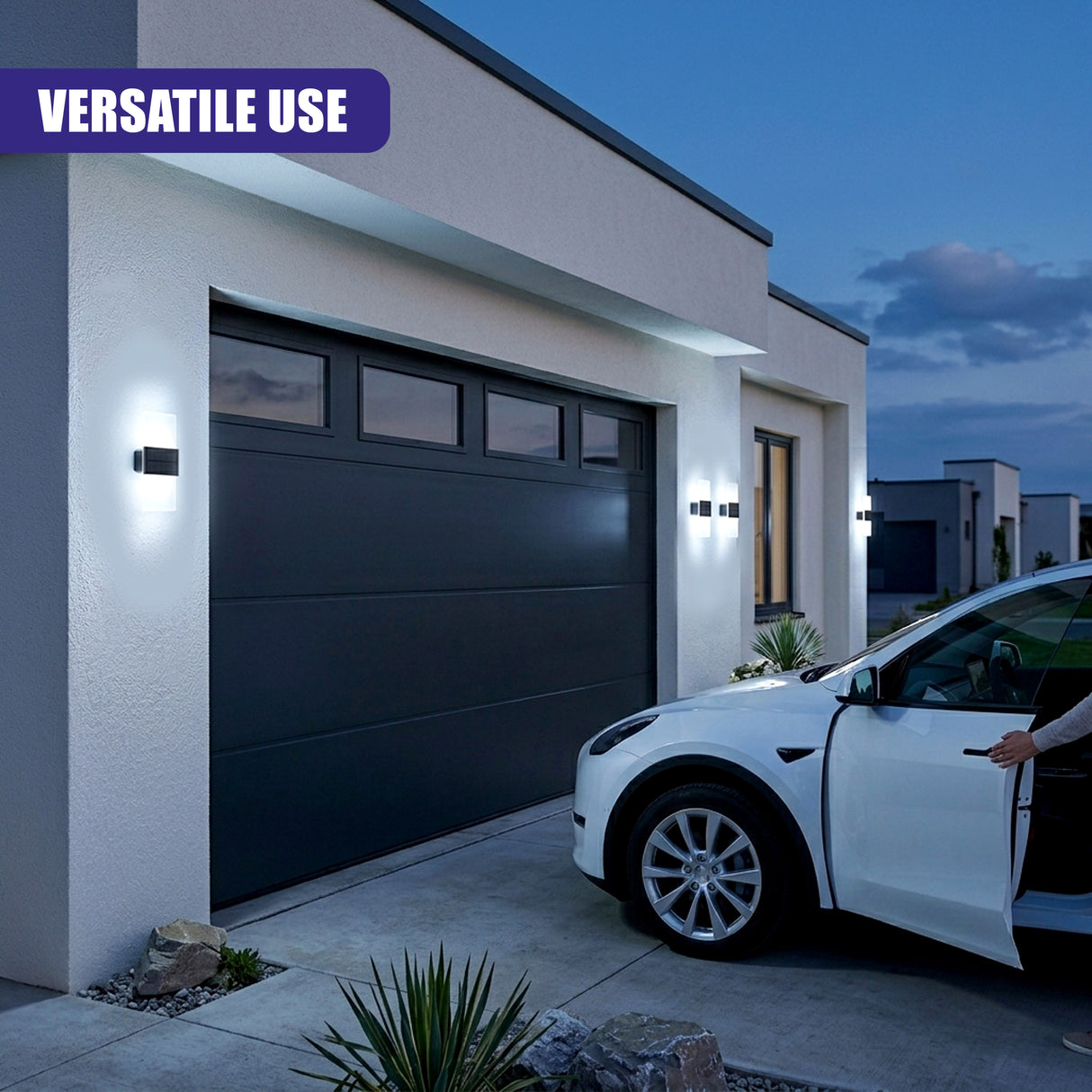Two rectangular acrylic wall lights illuminate the dark garage door of a modern suburban house.