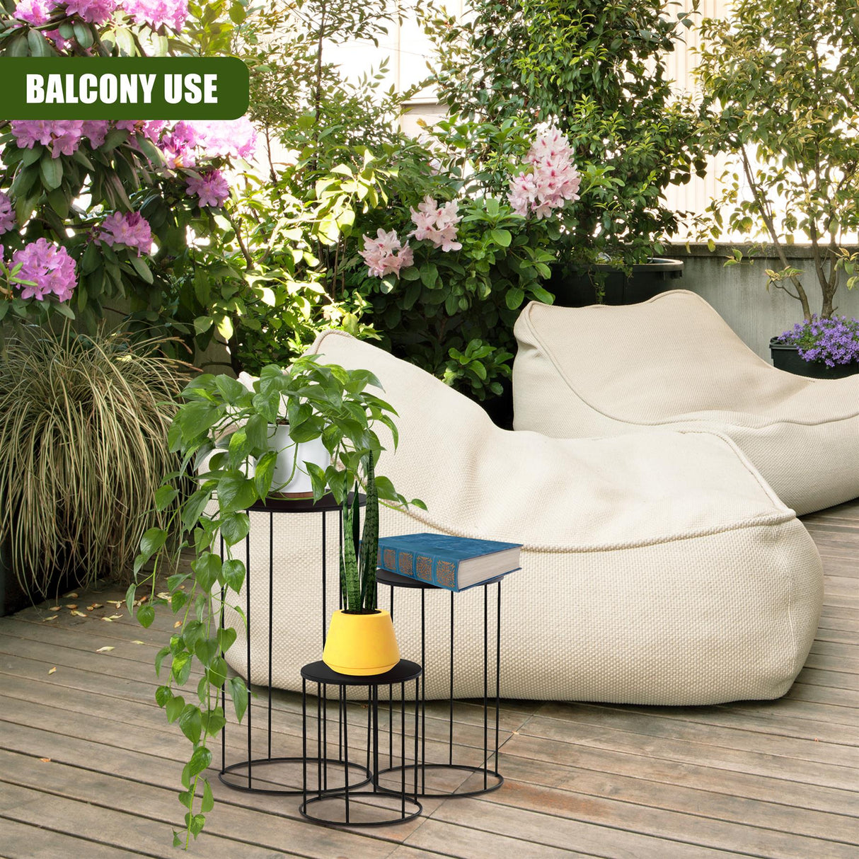 Tiered black metal plant stand set displaying greenery on a wooden surface.