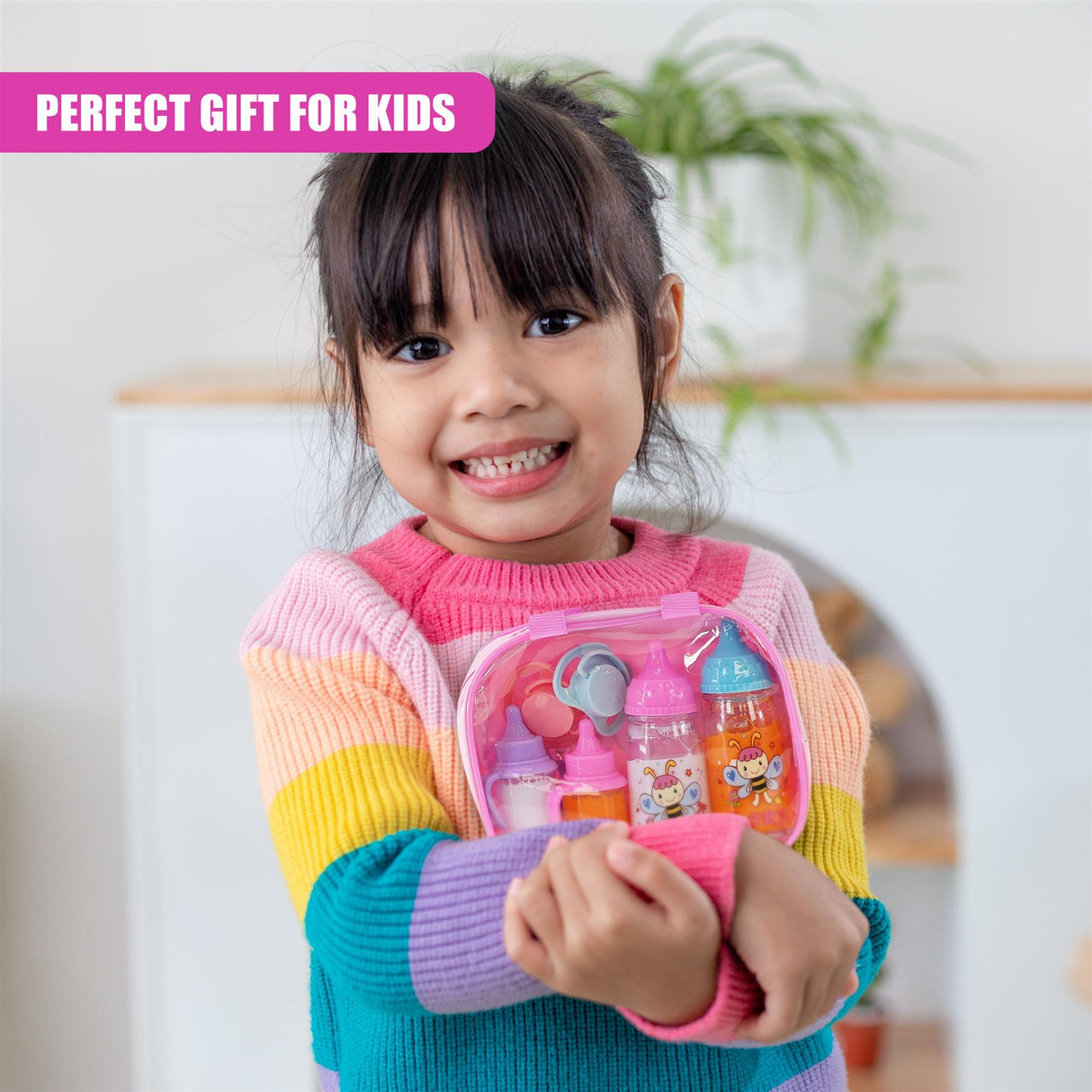 A smiling girl holds a pink case filled with doll accessories, including bottles and clothes.