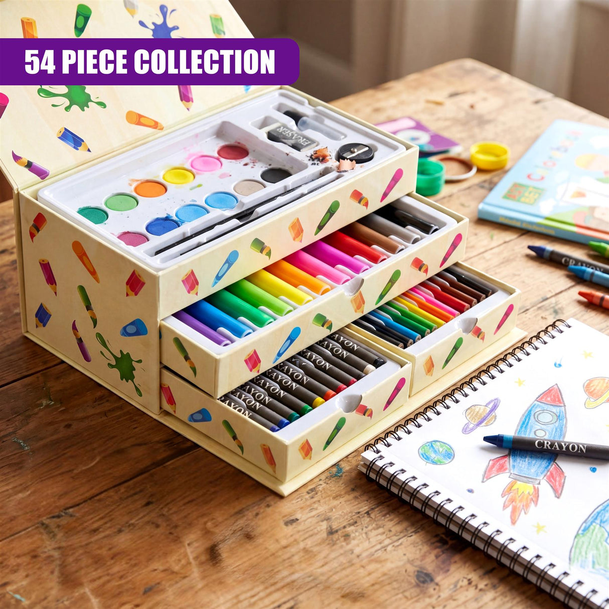 Open art set box holding watercolor palette, colored pencils, and crayons on a wooden surface.