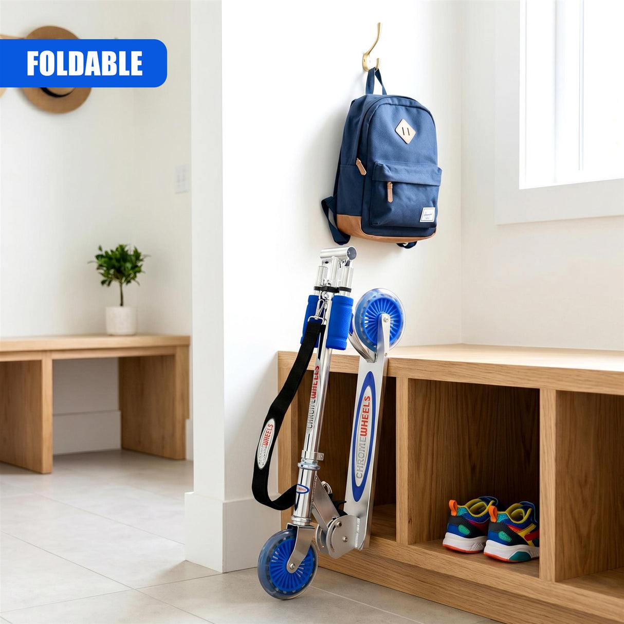 Blue, foldable kids scooter resting on a wooden shelf below a hanging navy blue backpack.