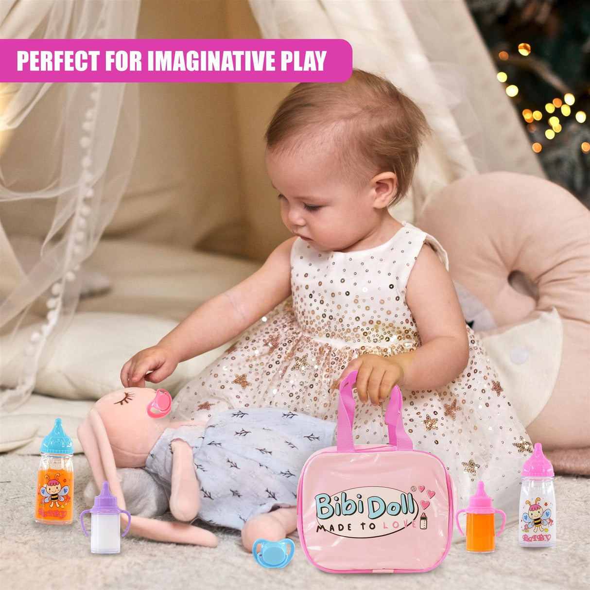 A baby interacts with a doll, accessories, a blanket, and a pink carrying pouch on a soft surface.