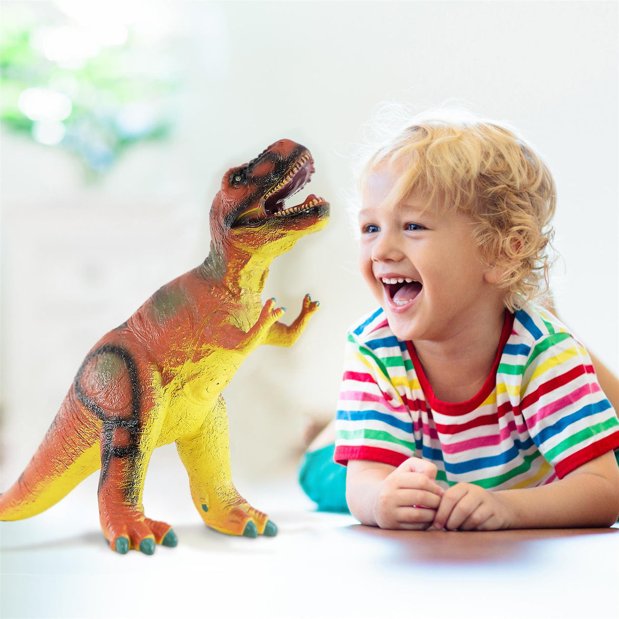 Child smiling next to a soft, plush T-Rex toy featuring yellow, brown, and red accents.