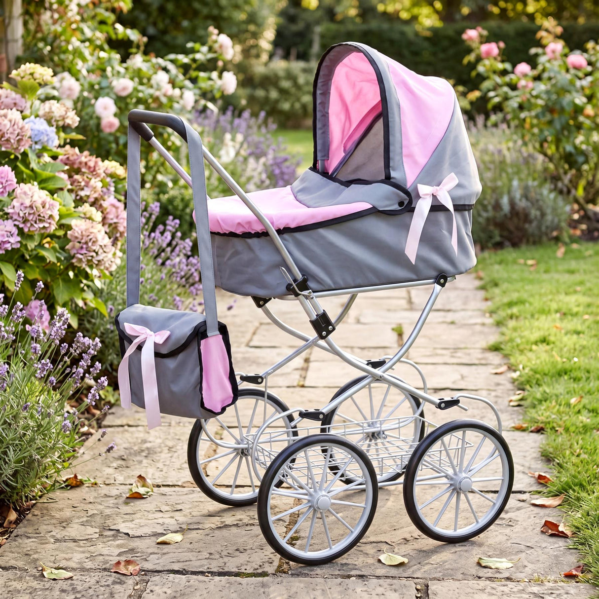 Doll stroller features a grey and pink fabric canopy, attached matching bag, and metal wheel frame.