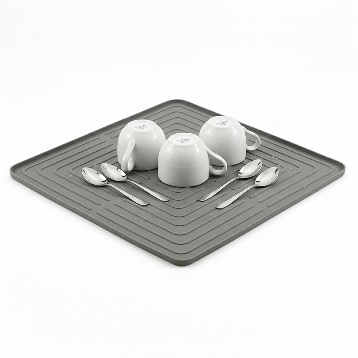 White dishes and metal spoons are displayed on a dark gray rectangular drying mat.