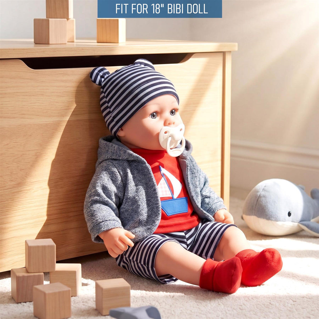 A doll is shown wearing a striped hat, grey cardigan, red and blue striped shorts, and red socks.