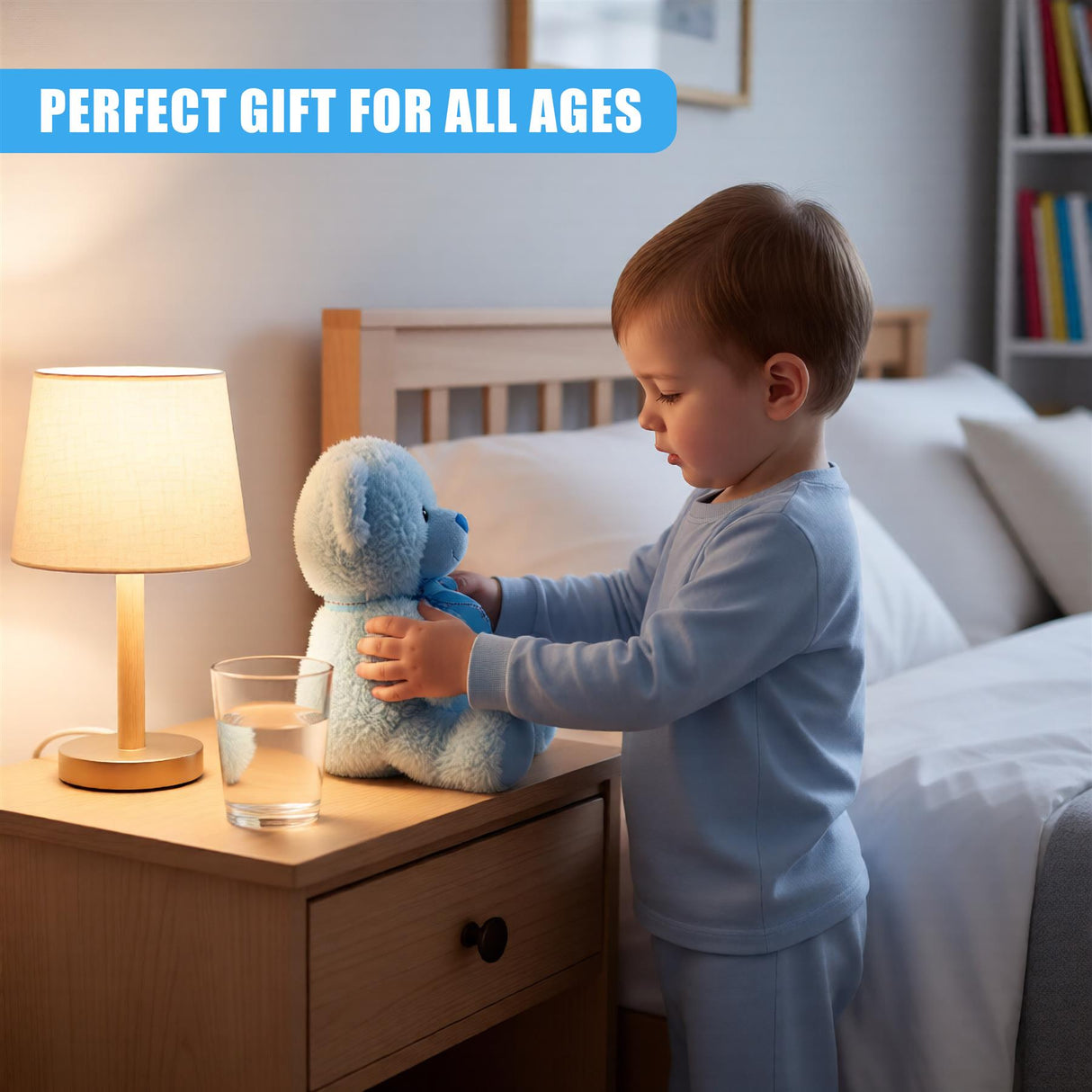 A young child in a bedroom, standing in front of a nightstand with a lamp, a glass of water, and a stuffed animal. The child is holding the stuffed animal, a soft blue bear, and is dressed in light blue pajamas. The room is dimly lit, with a soft glow from the lamp, and a bed with white sheets and pillows in the background. - UKBuyZone