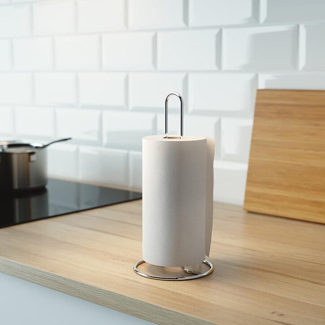 Two images of a sleek, chrome kitchen roll stand with a paper towel roll on top. It's placed on a counter next to a stove and a cutting board. - UKBuyZone