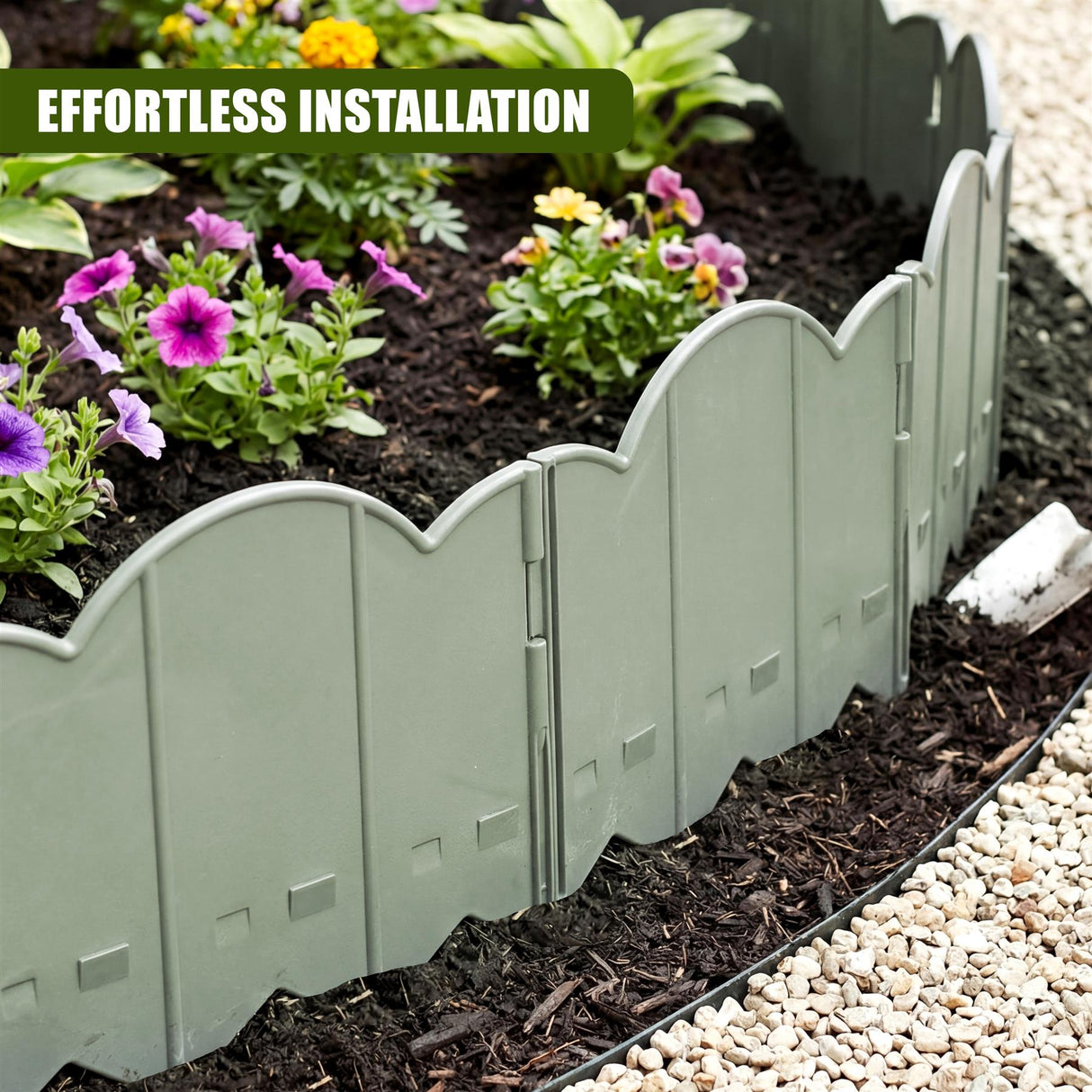 A curved, green metal garden edging fence separates a mulched flower bed filled with blooming plants.