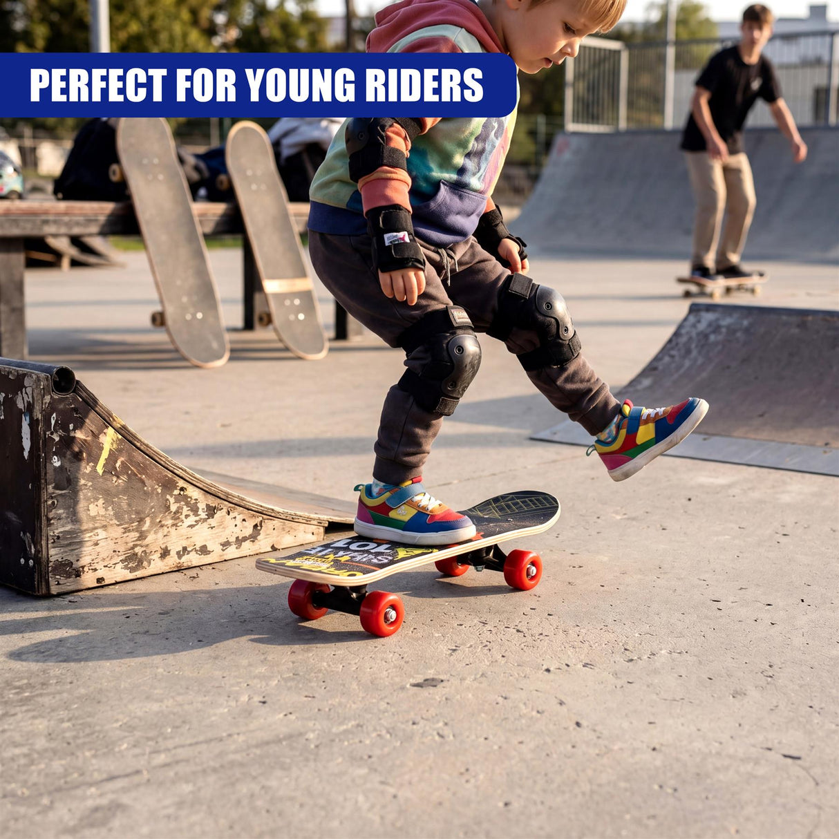 Young child riding a skateboard with red wheels in a concrete skate park setting.