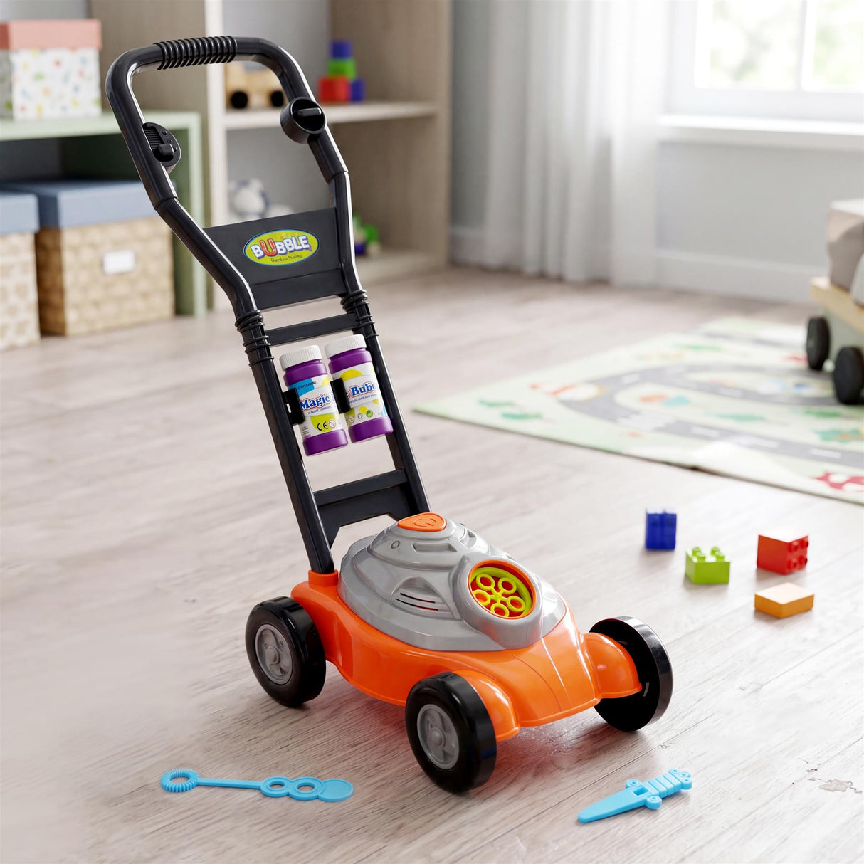 A toy bubble mower rests on a floor with scattered plastic building blocks and play tools.