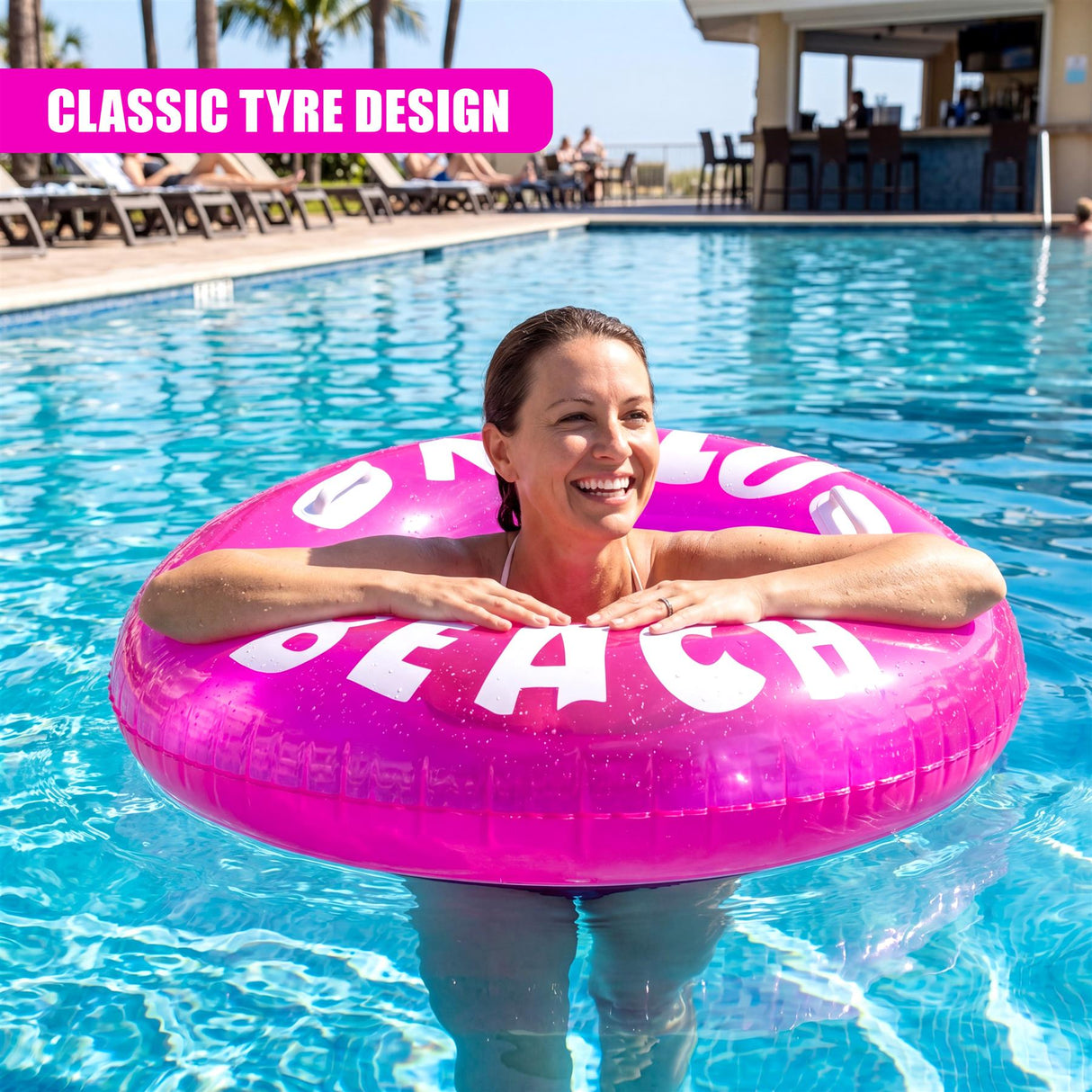 Smiling woman floating on a pink inflatable ring with white beach lettering in a blue pool.