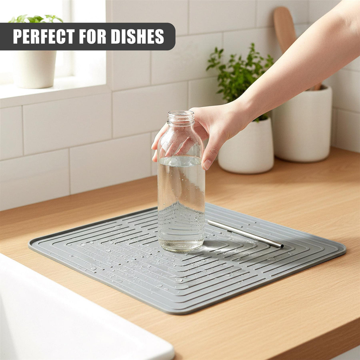 A gray drying mat with grooves rests on wood near a glass bottle filled with water.