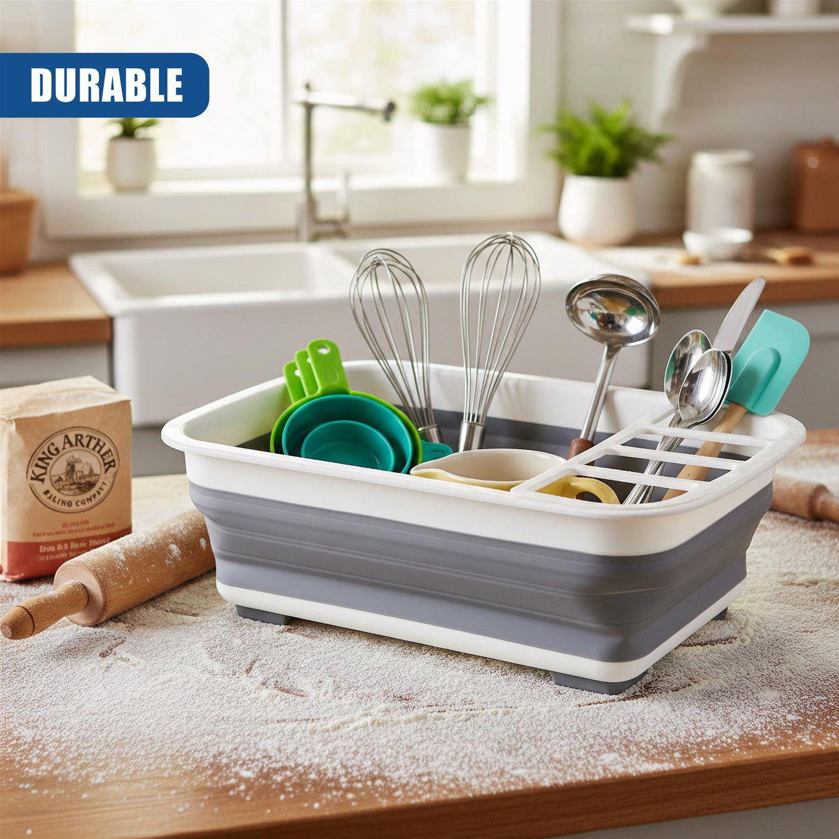 The collapsible dish drainer holds whisks, scoops, and various kitchen utensils on a flour-dusted counter.