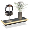 Black floating shelf displaying over-ear headphones, a potted flower arrangement, and integrated warm LED lighting.
