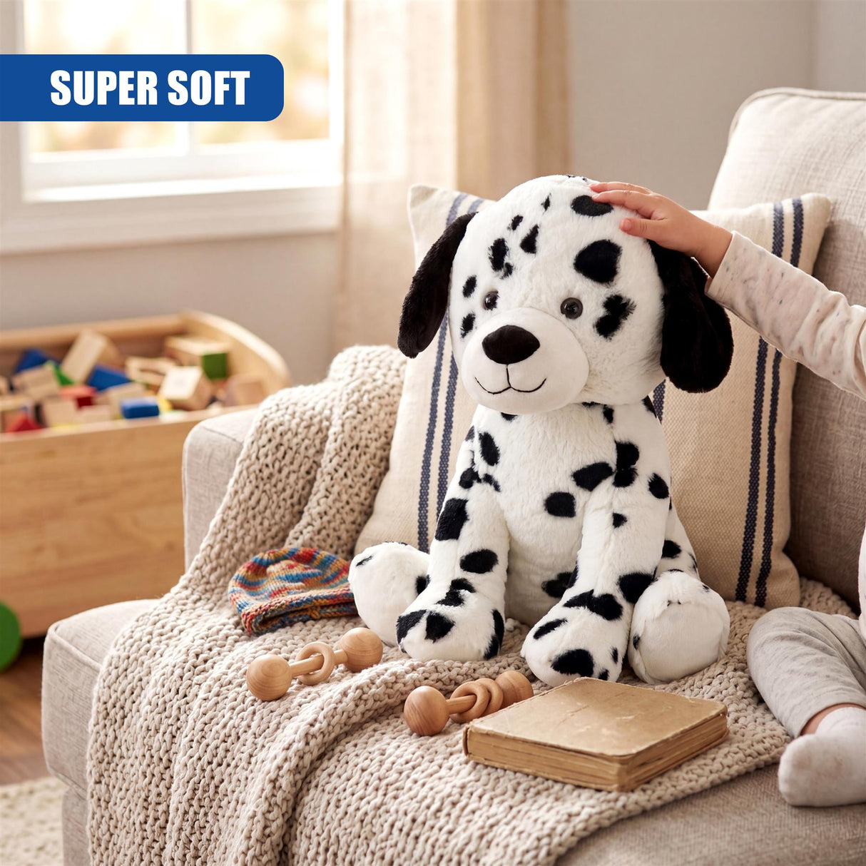 Dalmatian plush toy with a hand touching it, sitting among crocheted throw, wooden blocks, and books.