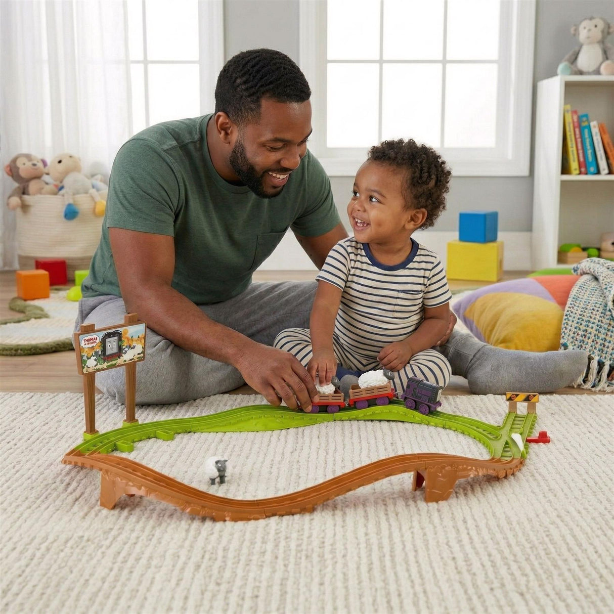 Father and son play with a green and brown train track set and toy pieces on a carpeted floor.