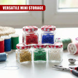 Five small glass jars containing colorful beads, placed among craft supplies and threads.