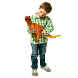 The image shows a boy holding a soft foam dinosaur toy with an attached long yellow tail.