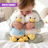 A child holds two white plush chicks sitting on a light green patterned cushion on a bed.