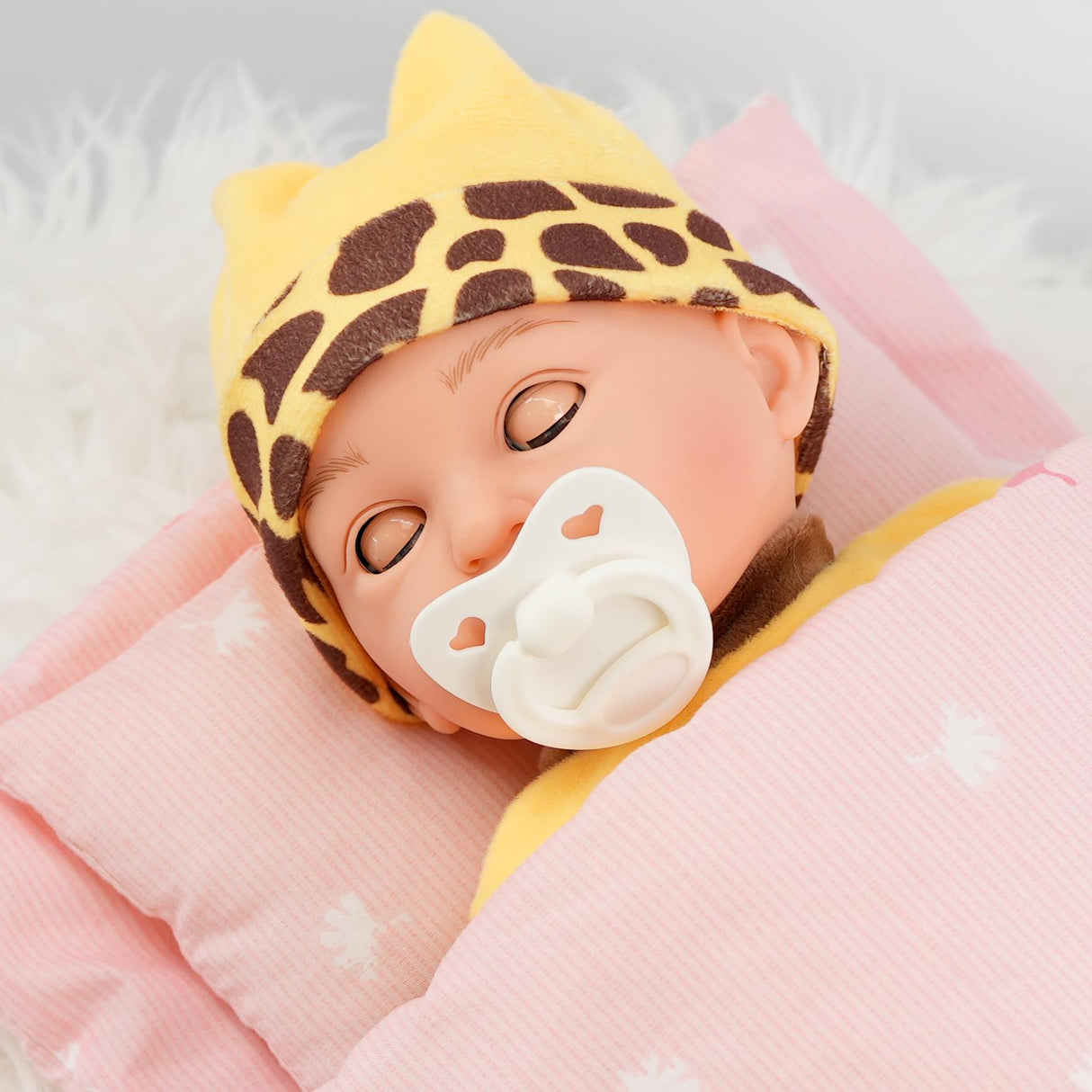 A baby doll in a jungle cat outfit sleeping on a pillow.