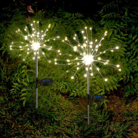 Two starburst solar powered stake lights from Geezie in a backyard setting at night.