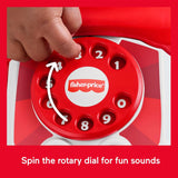 A hand is shown turning the numbered, red and white rotary dial of a toy telephone.