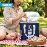 Woman opening a blue cooler bag on a blanket, placing wine bottles near bread and wine glasses.