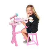 A young girl sits at a pink electronic keyboard with a microphone, playing and smiling. - UKBuyZone